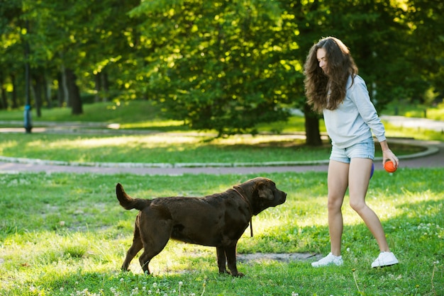 Женщина и ее собака, играющая на траве
