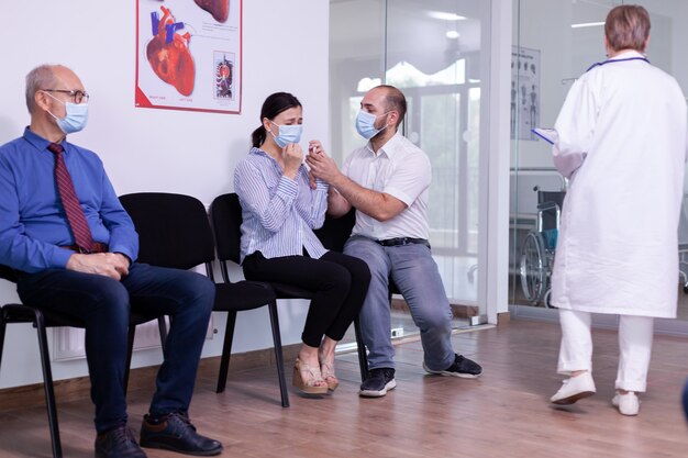 Woman and her husband crying in new normal hospital waiting room because clinic test results. Medical staff giving unfavorable news. Stressed man and woman during medic appointment.