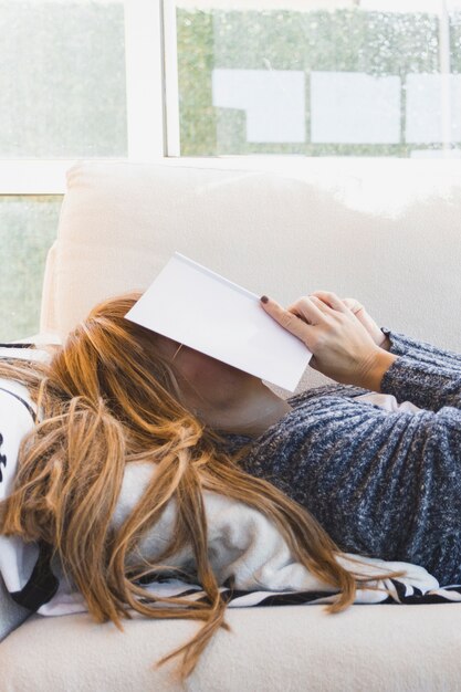 Woman hiding face behind book