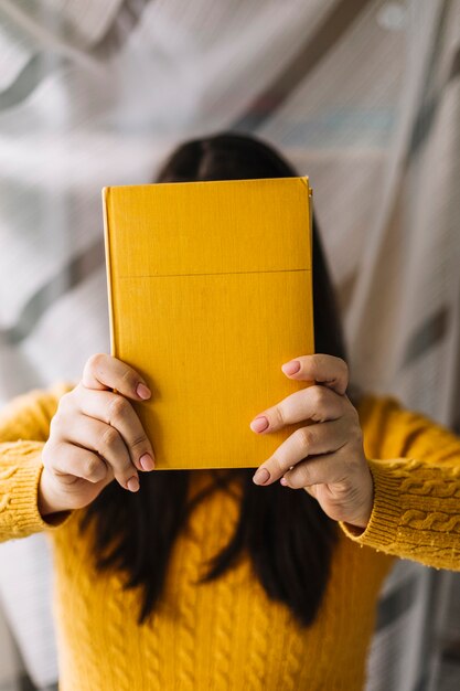 Woman hiding face behind book