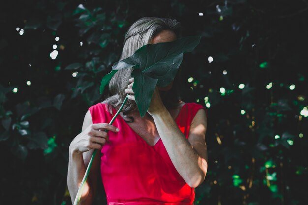 Woman hiding face behind leaf