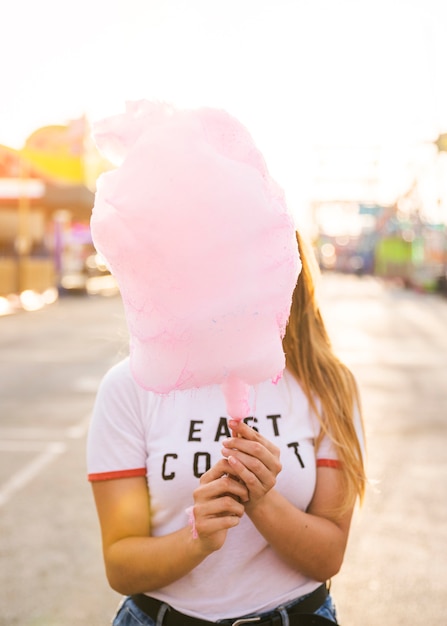 Free photo woman hiding her face in front of pink candy floss