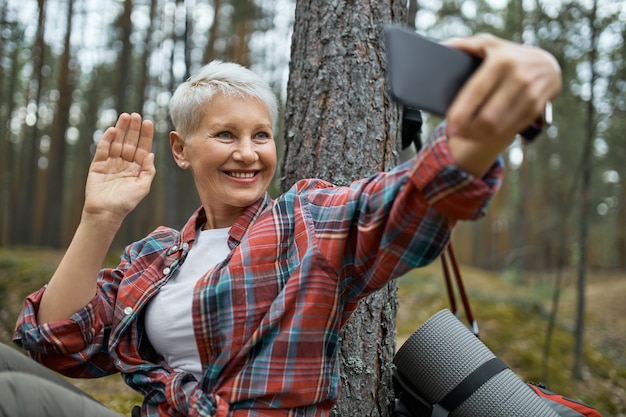 スマートフォンを使用して自分撮りをしているアクティブウェアの女性ハイカー