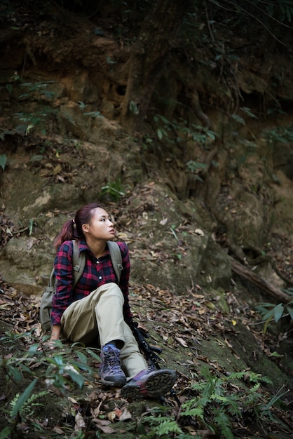 Женщина hiker в лесу отдыхает сидя рядом с водопадом пользуются с природой.