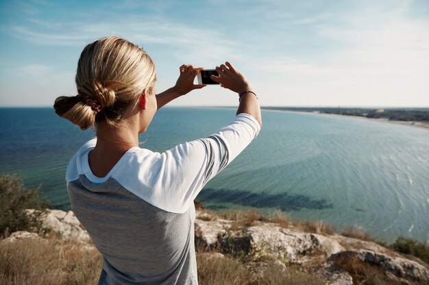 Woman hiker taking photo with smartphone