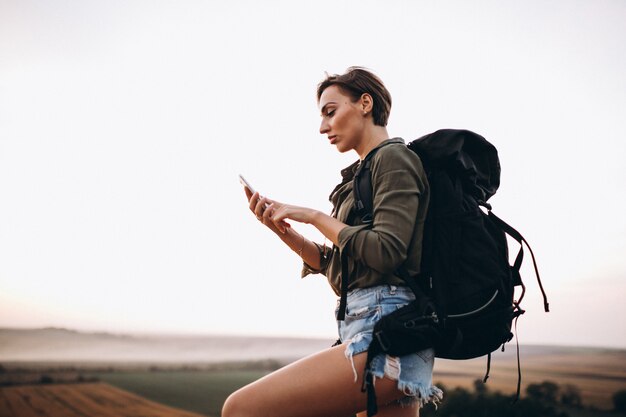 Женщина, путешествующая пешком в горах и использующая карточный телефон