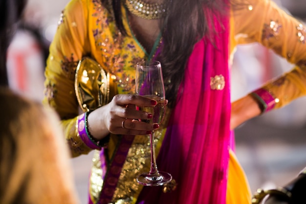 Woman in Hindu clothes holds glass of champagne