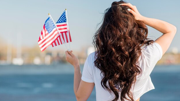 Woman holding 2 usa flags from behind