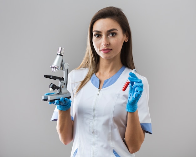 Бесплатное фото Женщина, держащая образец крови и микроскоп