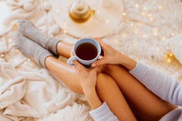 Бесплатное фото Женщина держит чашку чая, наслаждаясь зимними каникулами