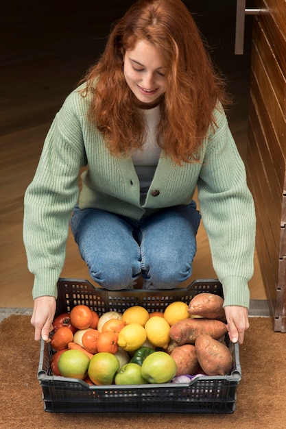 Бесплатное фото Женщина держит корзину с продуктами, доставленную к ее двери