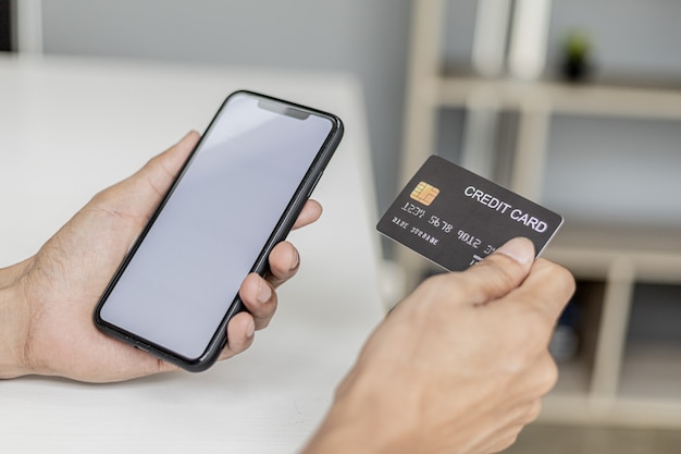 スマート​フォン​と​クレジットカード​を​持っている​女性​は​、​スマートフォンアプリ​で​購入した​商品​の​支払い​に​クレジットカード​情報​を​入力しています​。​オンライン​ショッピング​と​クレジットカード​決済​の​コンセプト​。