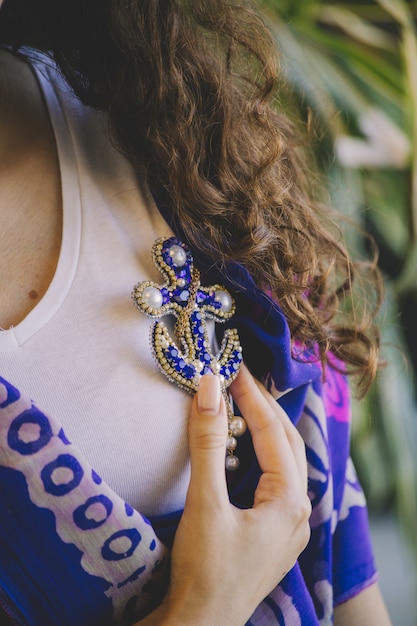 Woman holding an anchor shape jewelry pin