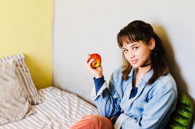 Woman holding apple on bed