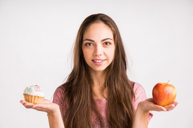 Woman holding and apple and a cupcake