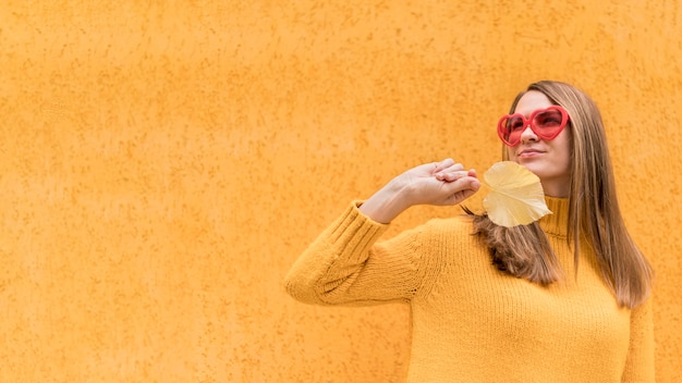 Free photo woman holding an autumn leaf with copy space