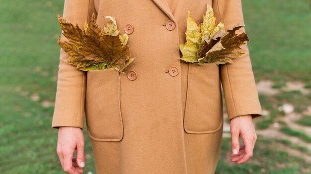 Woman holding autumn leaves in her pockets