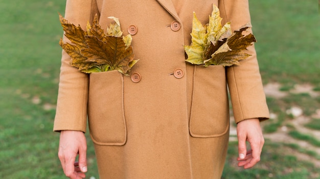 Женщина, держащая осенние листья в ее карманах