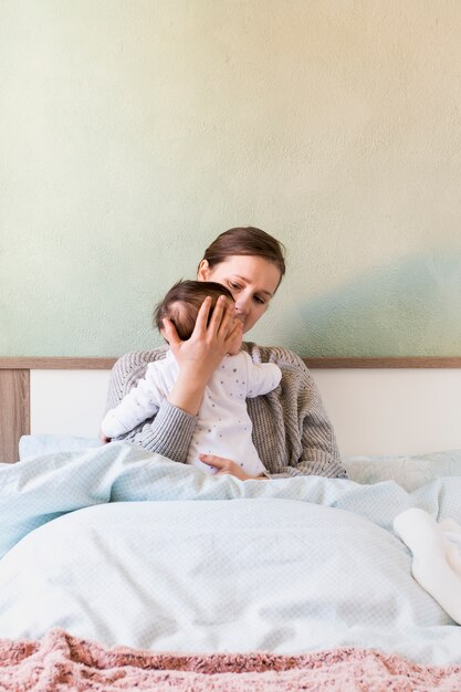 Woman holding baby in arms in bed