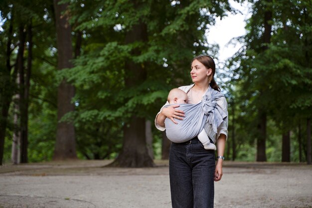 Woman holding baby outdoors front view