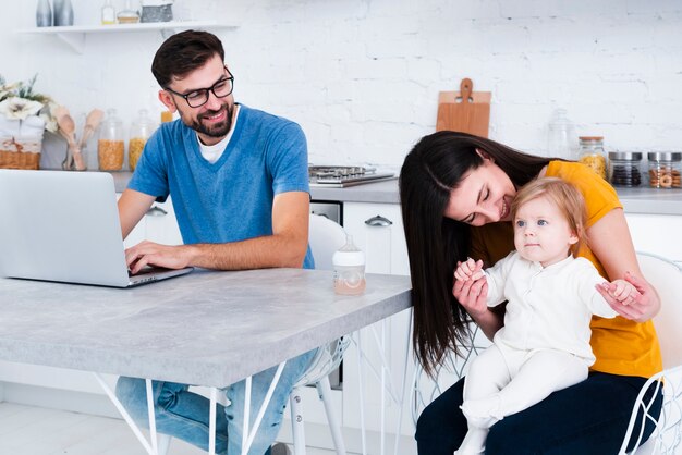 Woman holding baby with man working