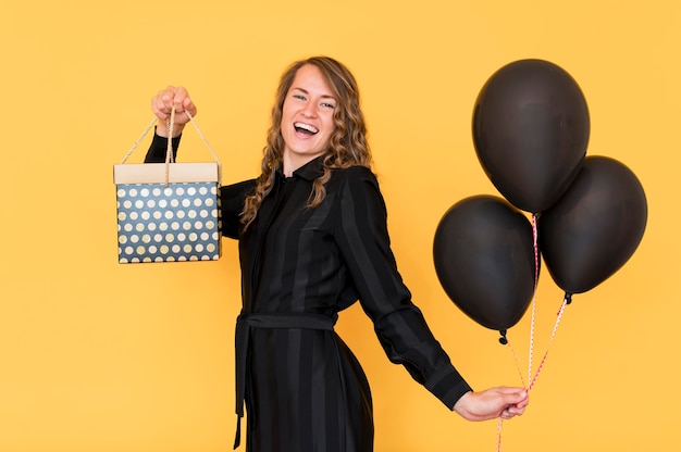 Woman holding balloons and gift box