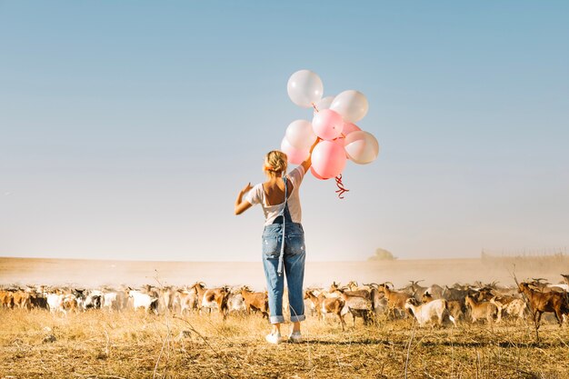 La tenuta della donna balloons vicino alla mandria di capre