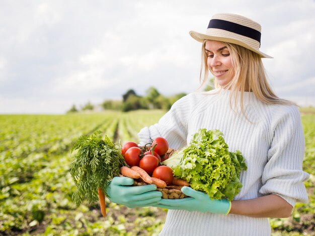 Женщина держит корзину, полную овощей