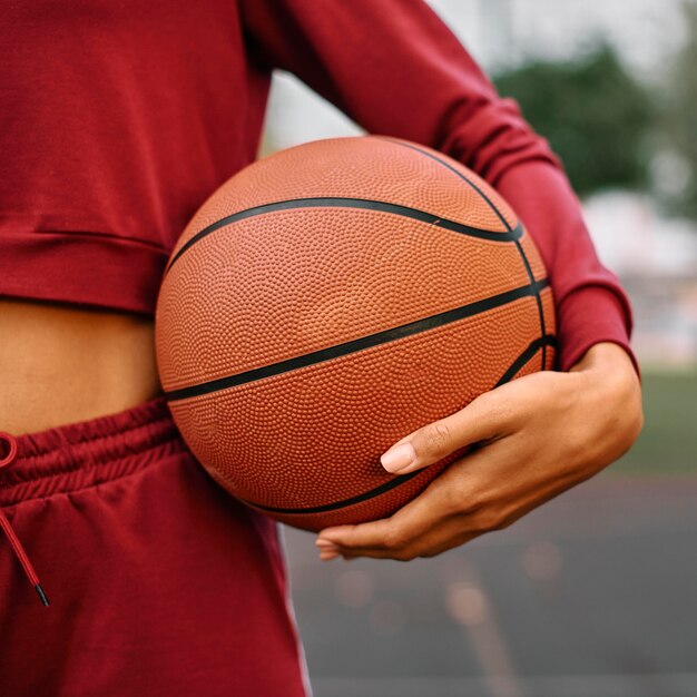 Женщина, держащая баскетбол на открытом воздухе крупным планом