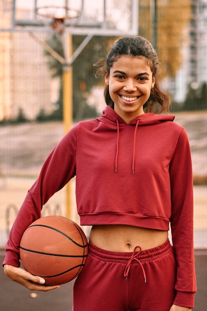 Женщина, держащая баскетбол на открытом воздухе