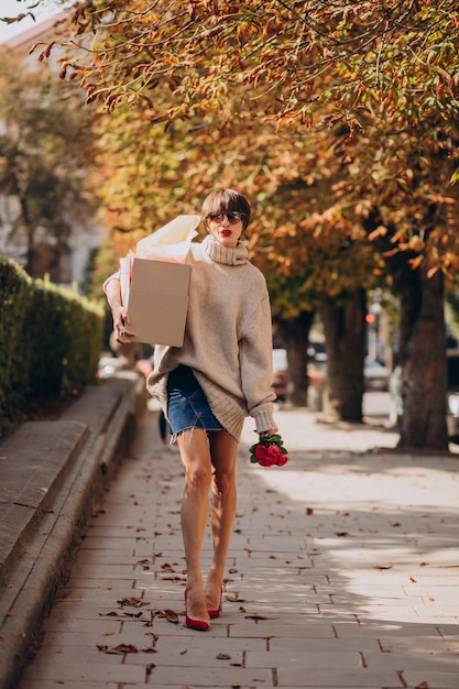 Woman holding big parcel box and walking in the street