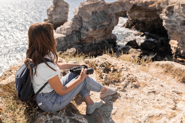 Woman holding binoculars on the beach