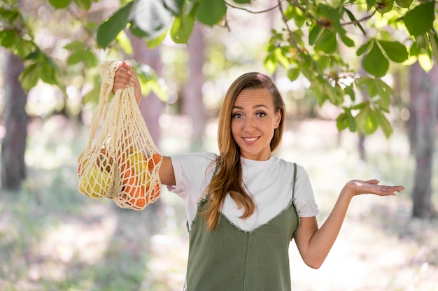 Женщина, держащая биоразлагаемый мешок с овощами и фруктами
