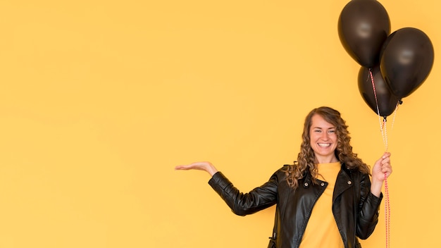 Woman holding black balloons copy space