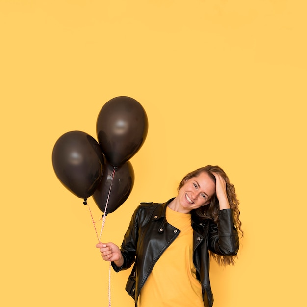 Woman holding black balloons front view