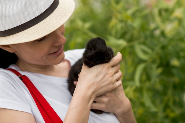 Free photo woman holding a black rabbit