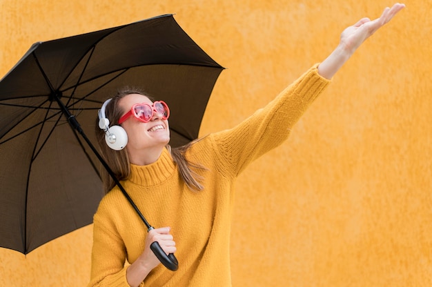 Free photo woman holding a black umbrella while rising her hand