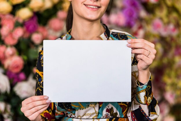 Woman holding blank paper in green house