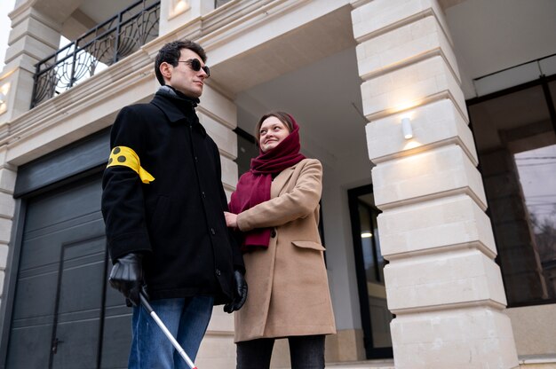 Woman holding a blind man's hand to help him walk