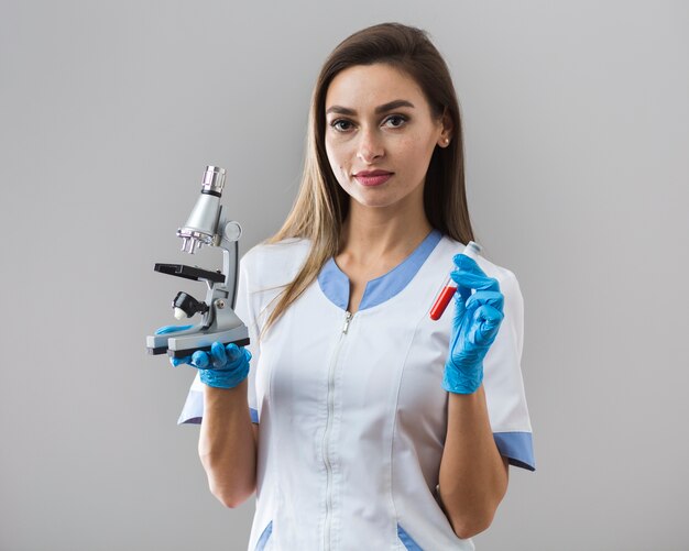 血液サンプルと顕微鏡を保持している女性