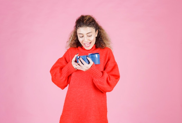 Free photo woman holding a blue heart shape gift box and looks surprized.