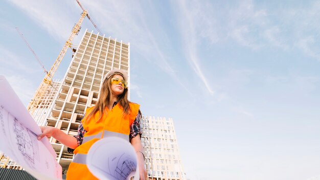 Woman holding blueprint and looking away