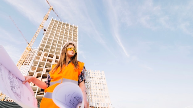 Woman holding blueprint and looking away