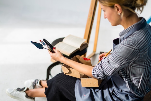 Woman holding book and art supplies