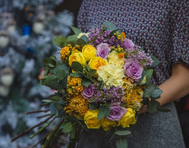 A woman holding a bouquet of fall autumn color flowers in the hand 