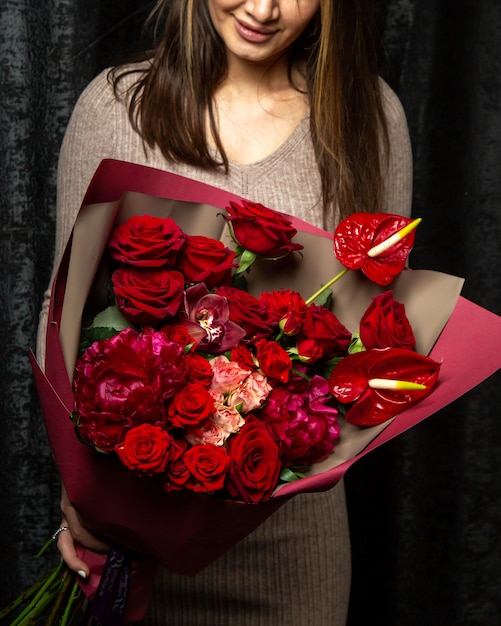 Free photo woman holding bouquet of pink and red roses anthurium and peony flowers