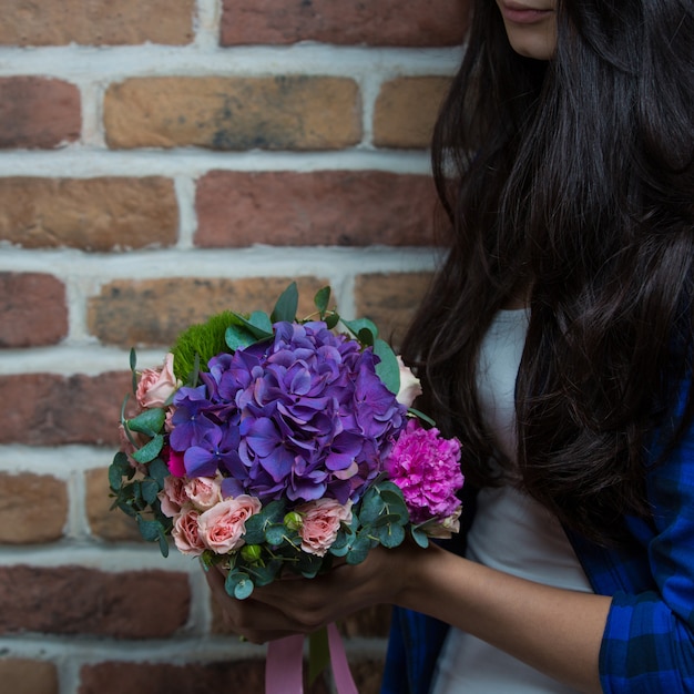 A woman holding a bouquet of purple flowers in the hand