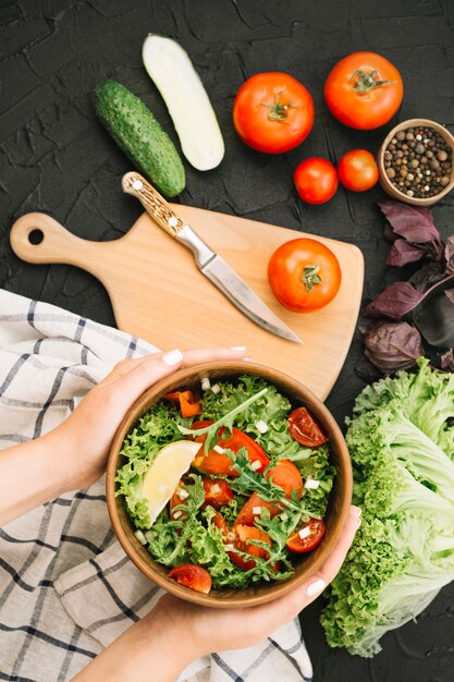 Woman holding bowl with vegetable salad