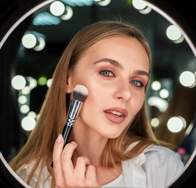 Woman holding brush looking at mirror