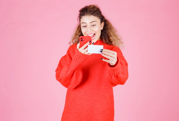 woman holding a business card and calling the number on it.